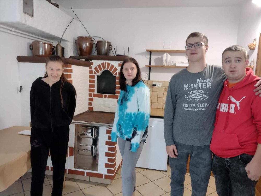Grupa uczniów pozuje do zdjęcia we wnętrzu kuchni. Tuż za nimi stoi duży piec kaflowy.