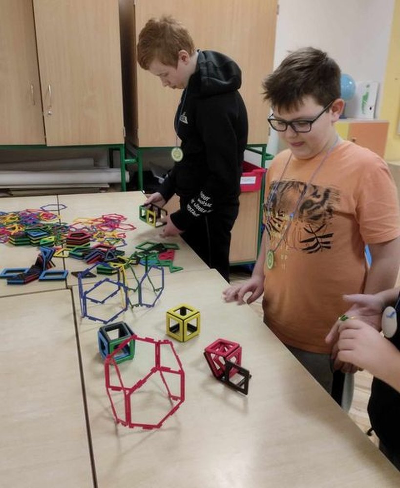 Na zdjęciu znajduje się dwóch uczniów układających różne figury z klocków magnetycznych i innych.