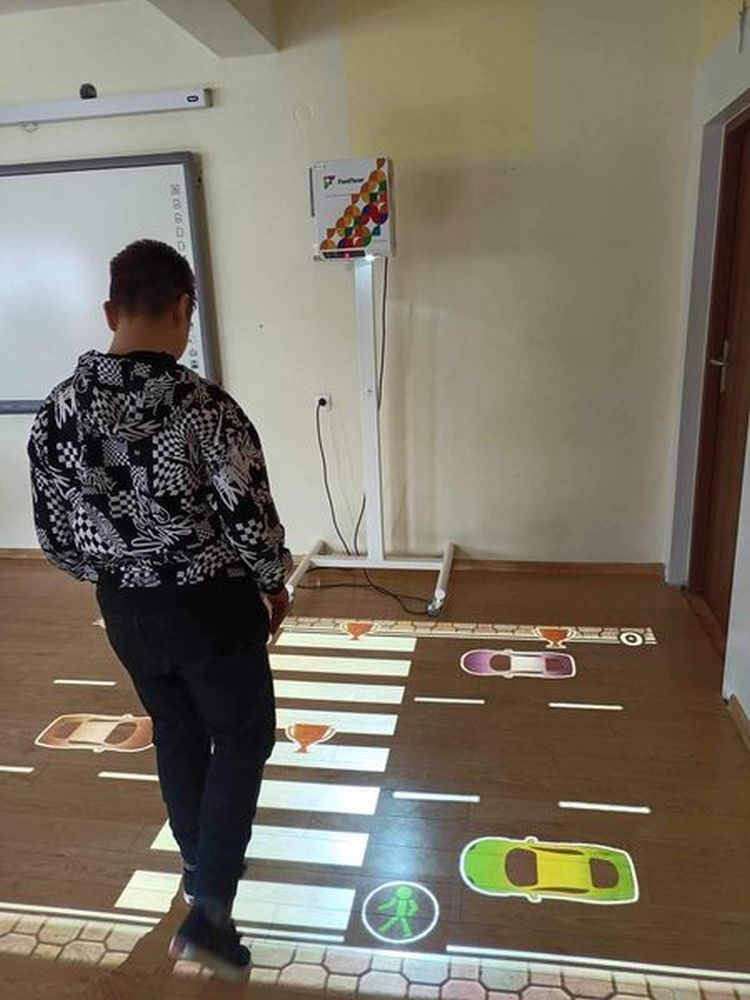 Uczeń korzysta z interaktywnej podłogi, na której przechodzi przez jezdnię.