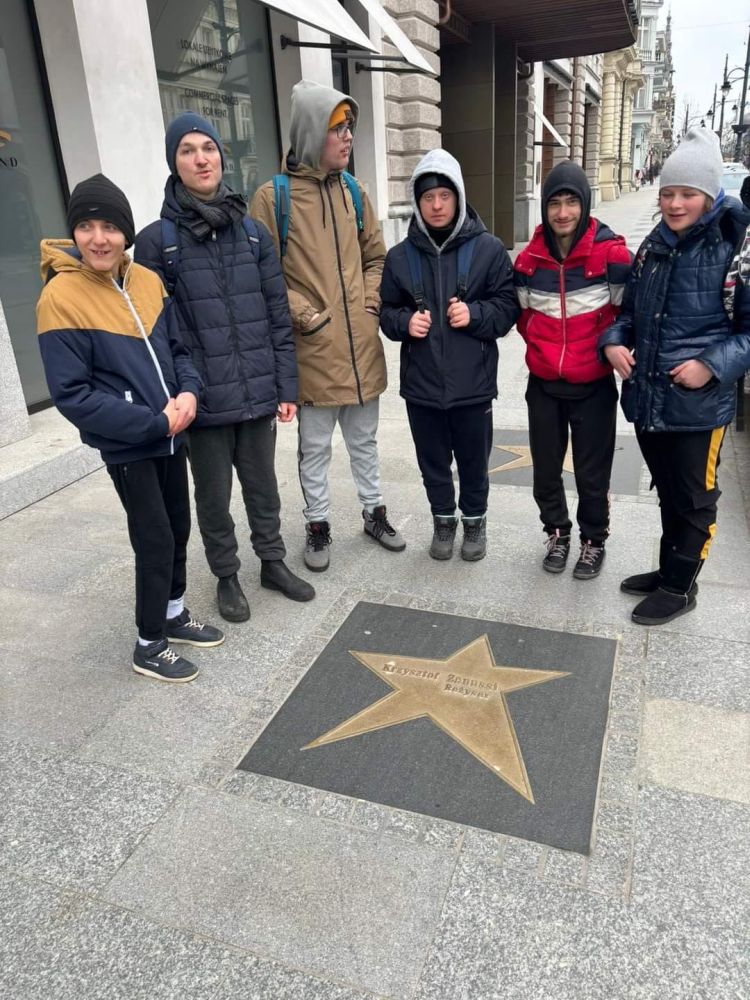 Uczniowie stoją na chodniku, na którym znajduje się złota gwiazda z napisem Krzysztof Zanussi.