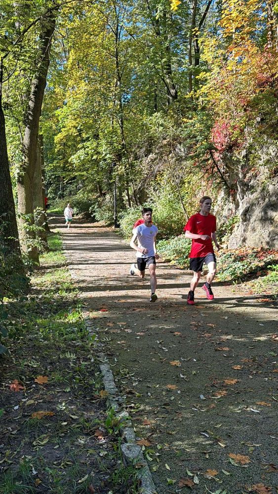 Uczeń biegnie przez park na zawodach sportowych.