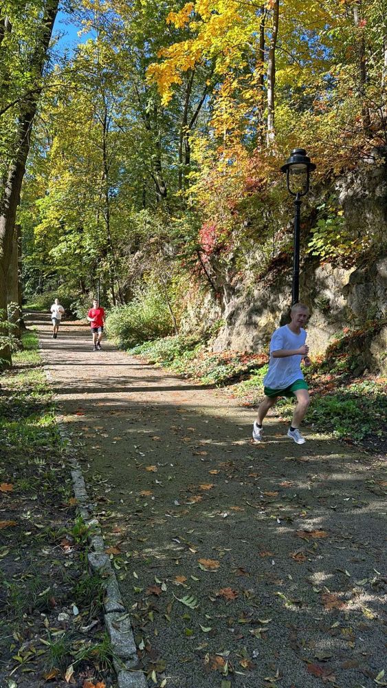 Uczeń biegnie przez park na zawodach sportowych.