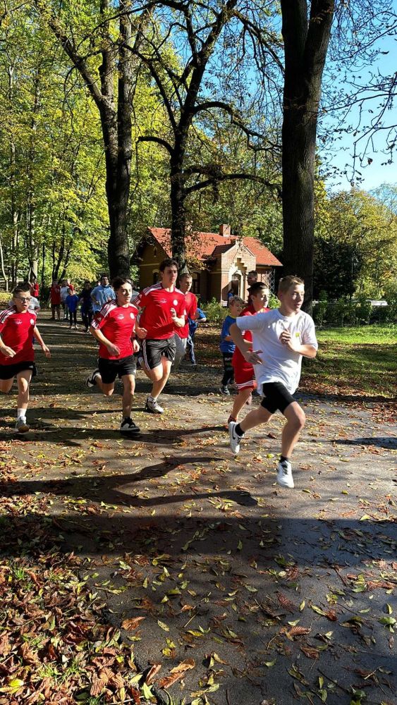 Uczeń biegnie przez park na zawodach sportowych.