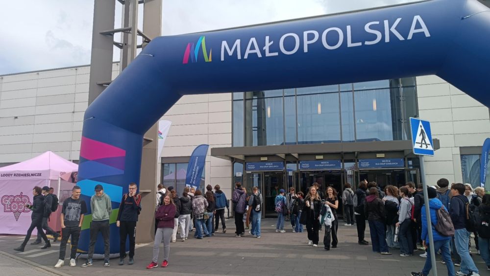 3 uczniów i 1 uczennica Naszego Ośrodka stoją pod napisem MAŁOPOLSKA, za nimi wielu uczniów innych szkół, którzy wchodza do budynku stojącego z tyłu.