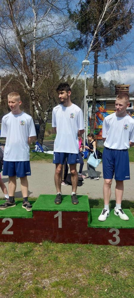 3 chłopców ubranych w białe stroje stoją na podium, na 1,2 i 3 miejscu w kategorii chłopców.