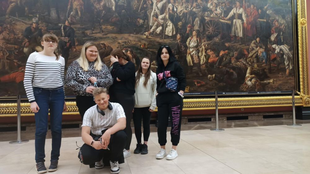 5 dziewczyn i 1 chłopak stoją przed dużym obrazem w Galerii Sztuki.